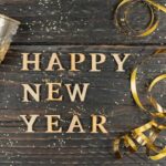 frohes-neues-jahr-grusskarte-glas-champagner-und-serpantine-von-goldfarbe-auf-holztisch-mit-verstreuten-konfetti_105596-6043